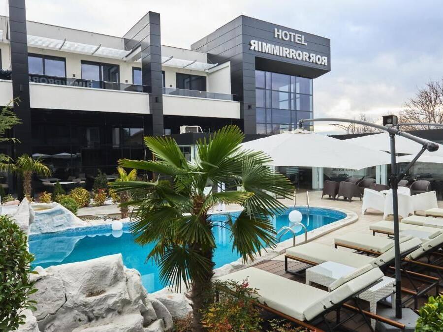 A hotel with a modern design, a swimming pool, and lounge chairs.