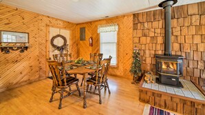 Un intérieur chaleureux en bois, avec une table à manger, des chaises, une cheminée et un ventilateur de plafond.