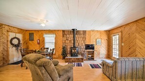 Un intérieur de chalet chaleureux avec une cheminée, des murs en bois, un coin repas et un espace salon confortable.