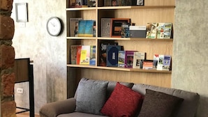 A living room with a grey sofa, a wooden coffee table, and a bookshelf filled with books and a clock. - Hostel Boulevard Prishtina (Pristina)