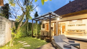 A modern outdoor patio with a wooden deck, lounge chairs, and a covered seating area. - 2 Bedroom Villa in Seminyak Bali with private pool and enclosed Living Room. (Seminyak)