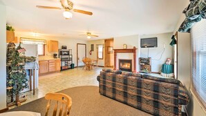 A living room with a fireplace, a sofa, a dining area, and a kitchen. - Rustic Iowa Cabin: 10 Mi to Maquoketa Caves (Spragueville)