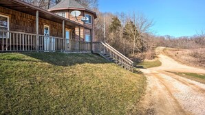 A wooden cabin with a porch and a satellite dish, surrounded by a dirt road and trees. - Rustic Iowa Cabin: 10 Mi to Maquoketa Caves (Spragueville)