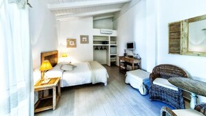 Un dormitorio con cama, mesita de noche, lámpara y un escritorio pequeño con silla.