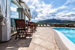 Ein Poolbereich mit Liegestühlen und einem Tisch mit Blick auf ein Gebirge.