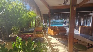 A covered outdoor area with a pool, seating, and lush greenery. - No 22 Hotel Riders' Inn (Ula)