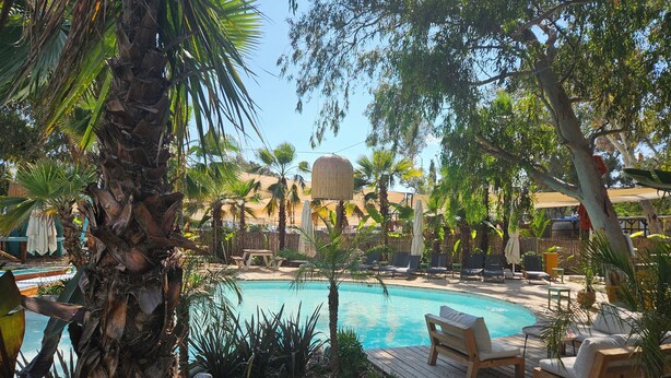 A pool area with lounge chairs and a wooden deck. - No 22 Hotel Riders' Inn (Ula)