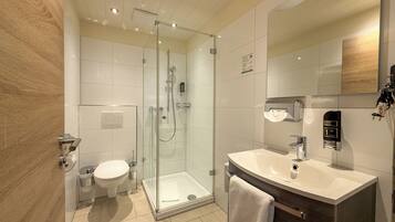 Ein modernes Badezimmer mit einer Duschkabine, einer Toilette und einem Waschtisch mit Waschbecken und Spiegel.