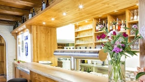 Una zona de bar con estantes de madera, taburetes y una grifo de cerveza.