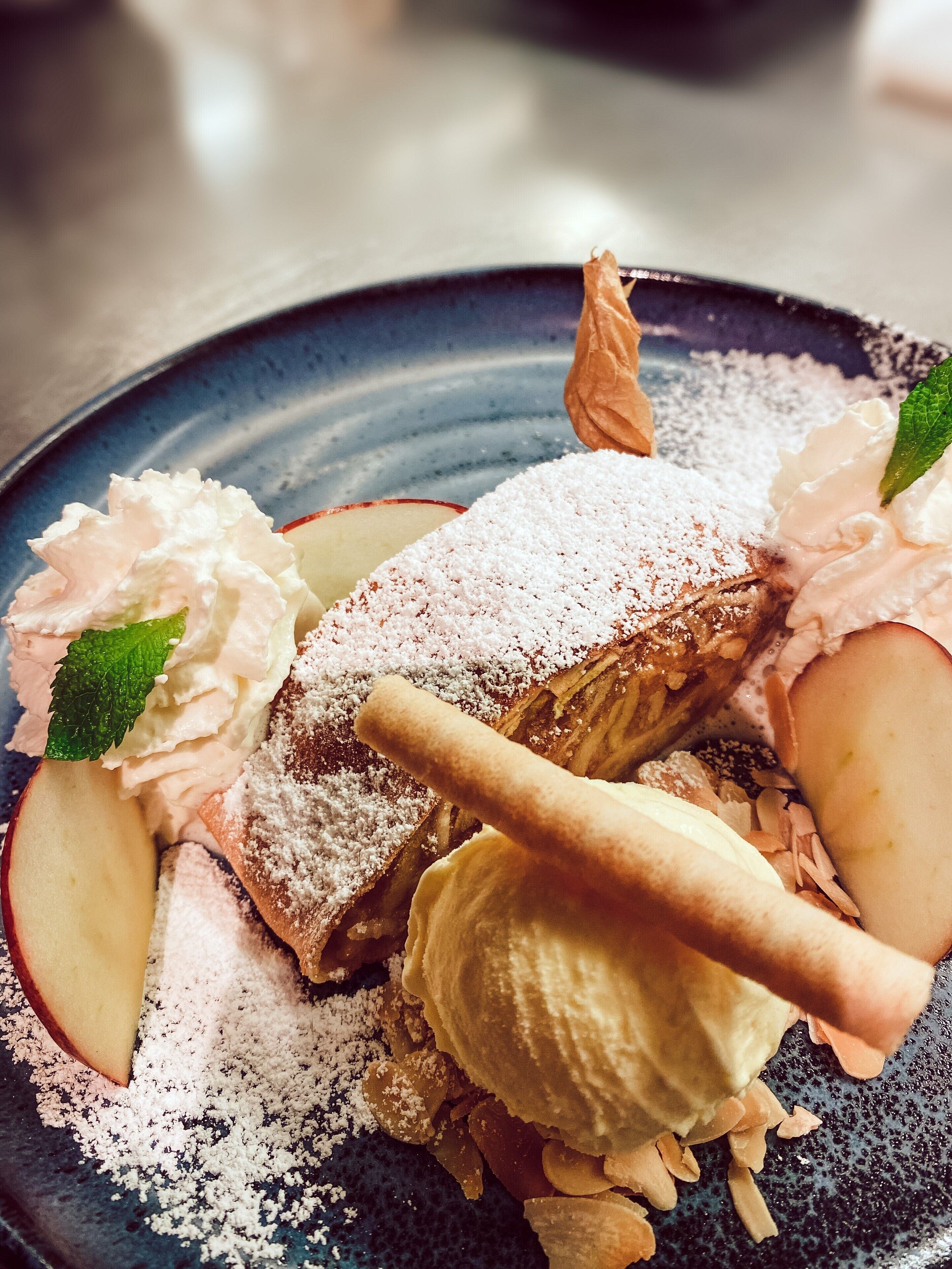 A dessert plate with various toppings including whipped cream, powdered sugar, and a pastry.