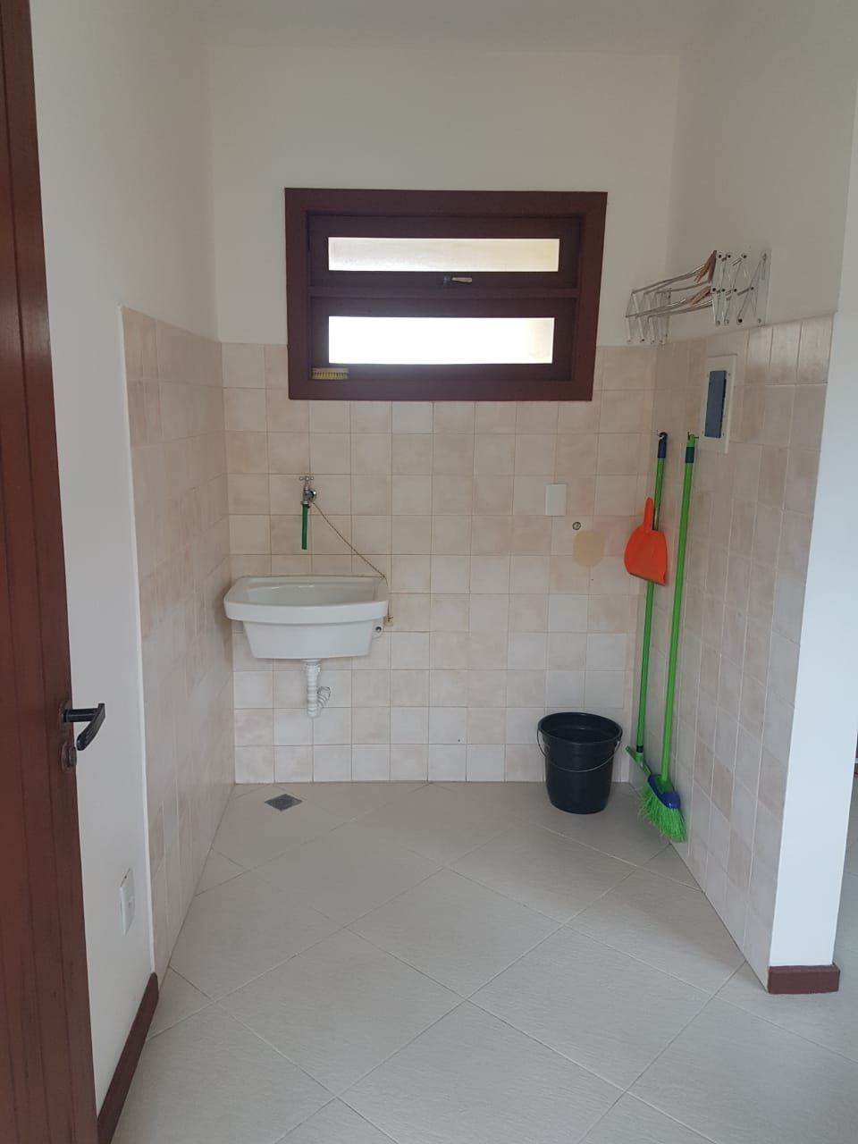 Un bagno piccolo con un lavandino, una finestra e articoli per la pulizia.