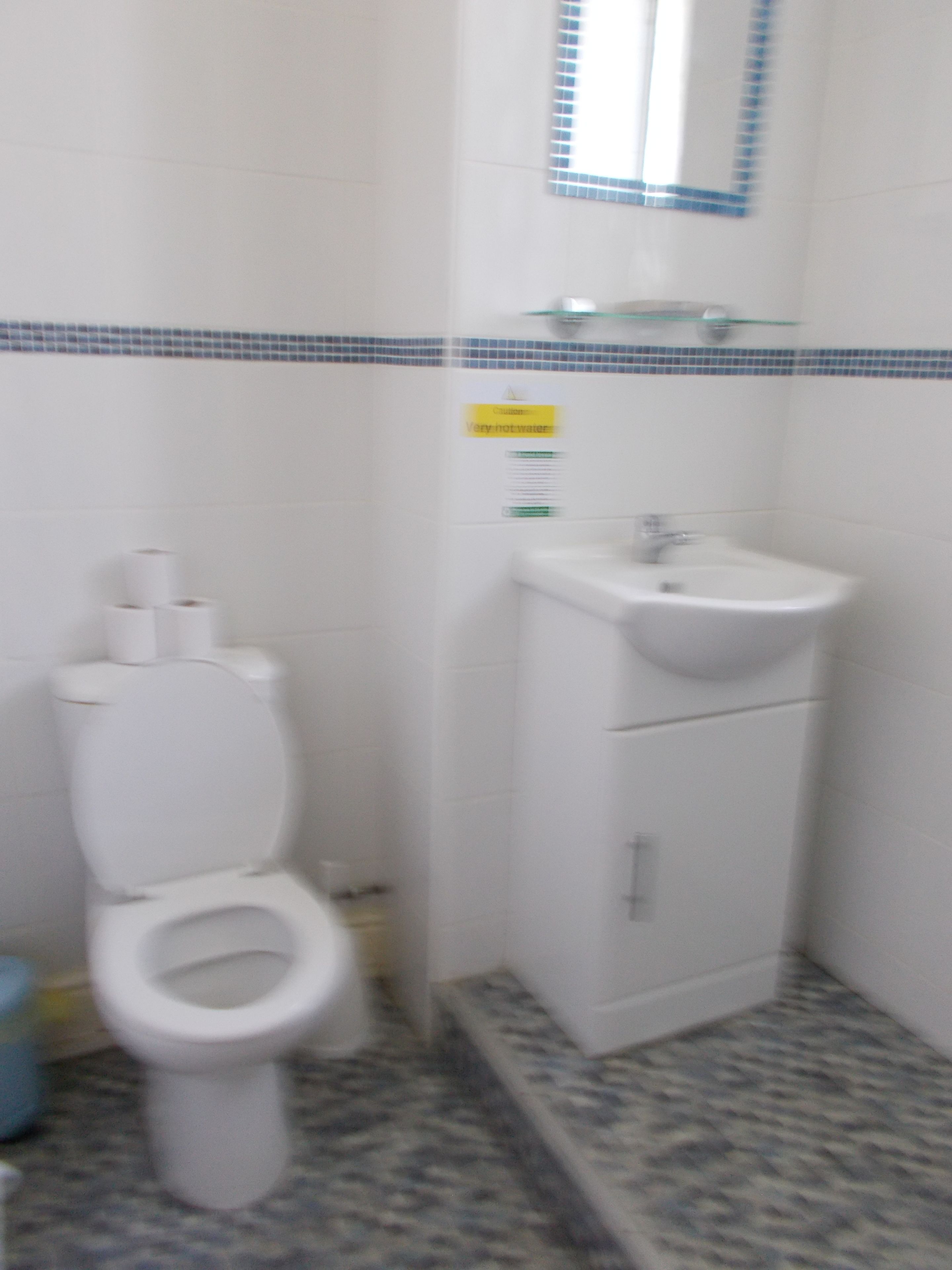 A bathroom with a toilet, sink, and blue-tiled wall.