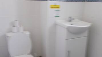 A bathroom with a toilet, sink, and blue-tiled wall.