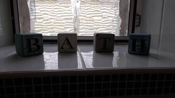Quatre blocs de construction portant les lettres B, A, T, H, posés sur un rebord de fenêtre.