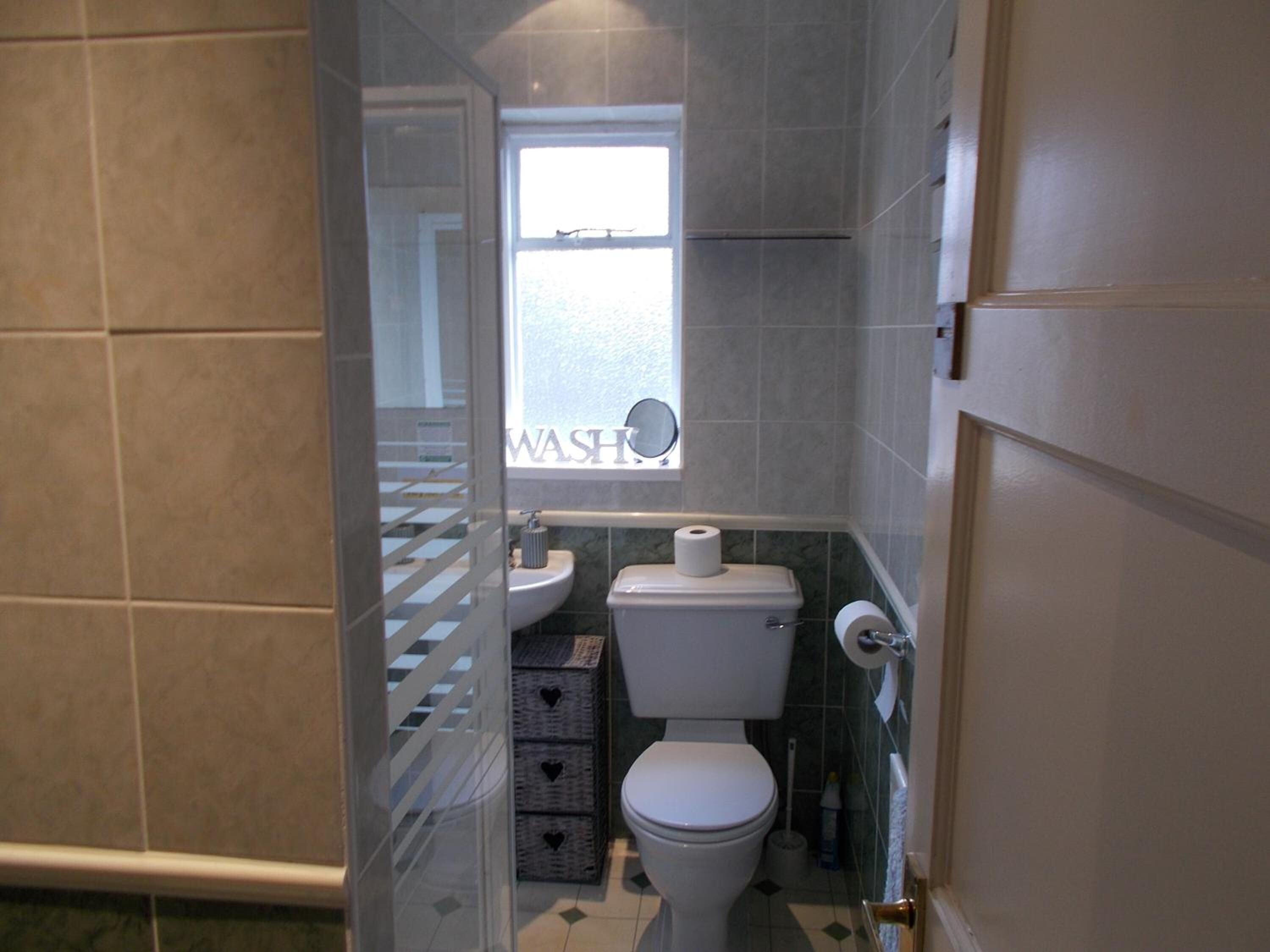 Et lille badeværelse med toilet, håndvask og et vindue.