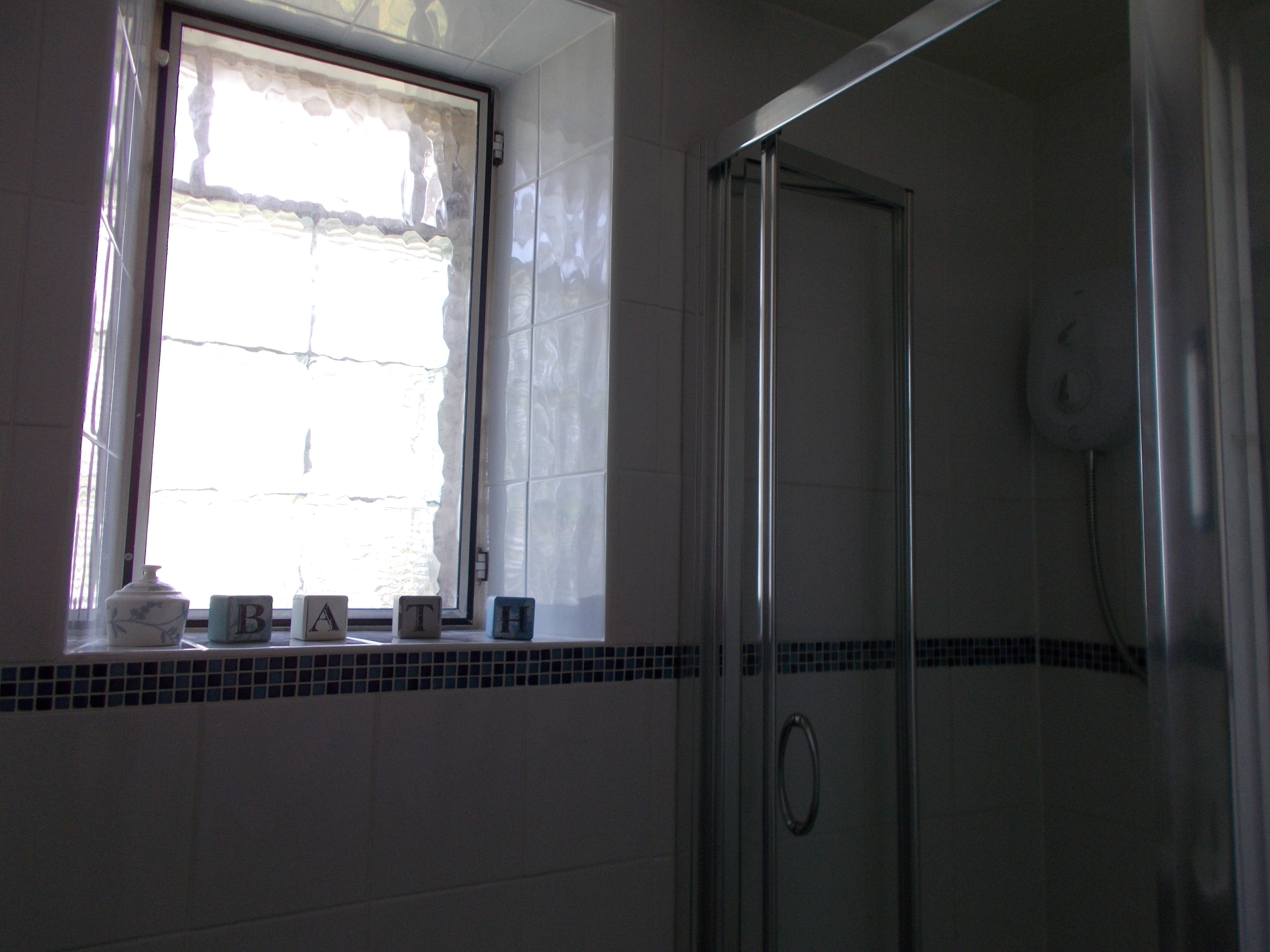 Ein Badezimmer mit Fenster, Dusche und Fliesen.