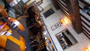 A multi-level hotel lobby with wooden furniture, a staircase, and framed pictures on the walls. - The White Lion Hotel (Machynlleth)