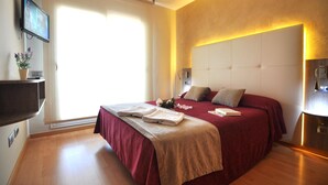 Een moderne hotelkamer met een groot bed, een flatscreen televisie, een nachtkastje en een groot raam.