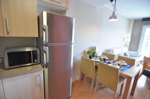 Cocina compacta con refrigerador, microondas y mesa de comedor con sillas.