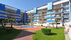 Um hotel com vários andares, varandas, piscina e um pátio ajardinado.
