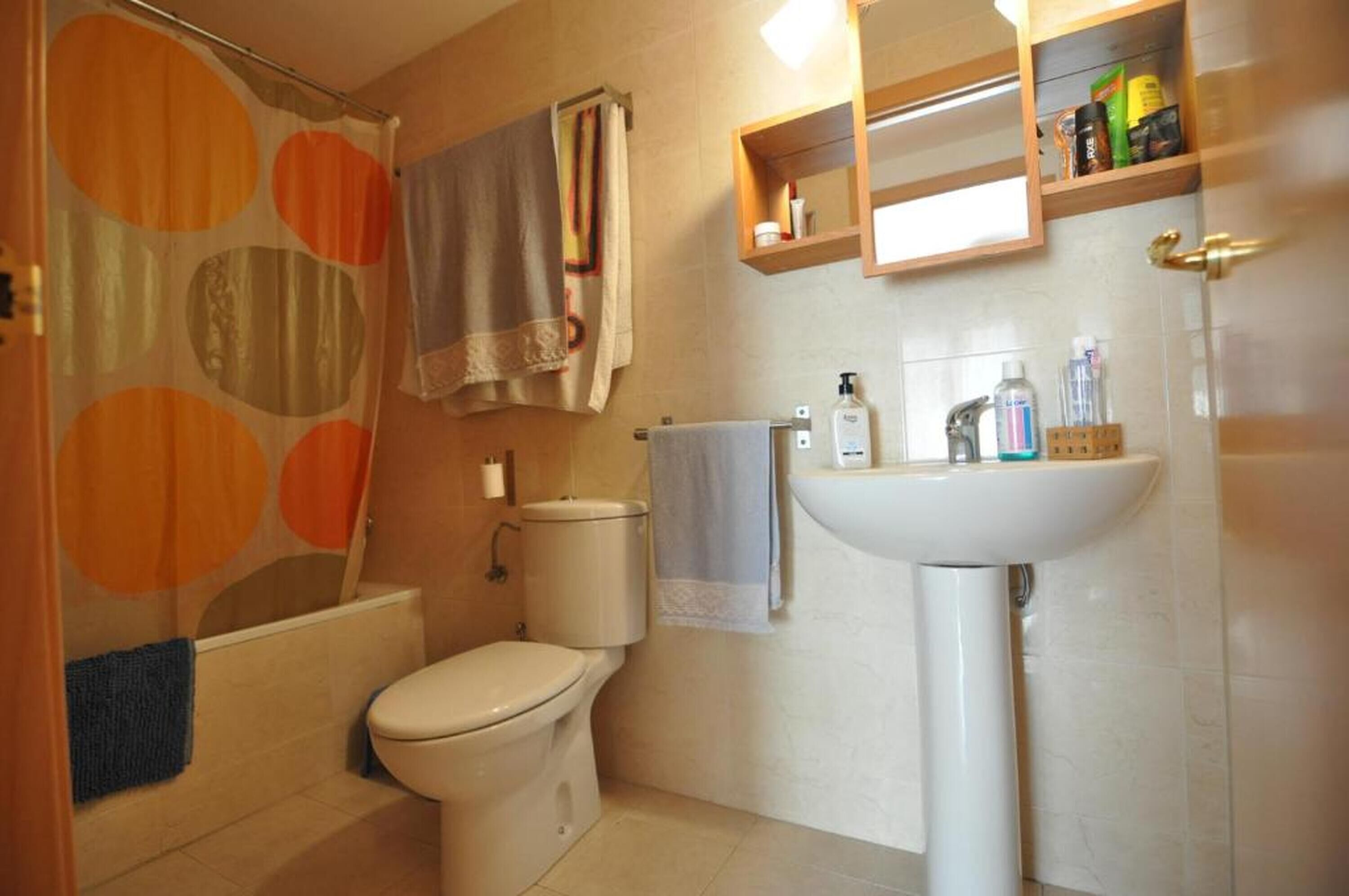 Een badkamer met toilet, wastafel en douchegordijn.