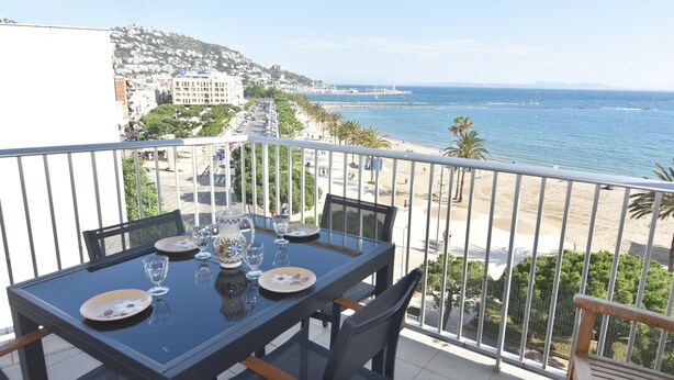 Ein Balkon mit Tisch für zwei Personen, mit Blick auf Strand und Stadtlandschaft.