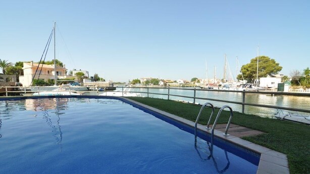 En swimmingpool med utsikt över båtar och byggnader i bakgrunden.