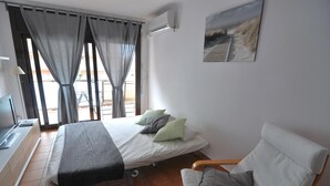 Een kamer met een bed, een stoel, een televisie en een raam met gordijnen.