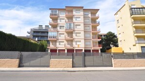 A multi-story residential building with balconies, a gated entrance, and a clear sky. - Vacation rental in Roses, Costa Brava: Cozy apartment 400 meters from the beach, capacity for 4 people, with terrace and amenities. (Rosas / Roses)