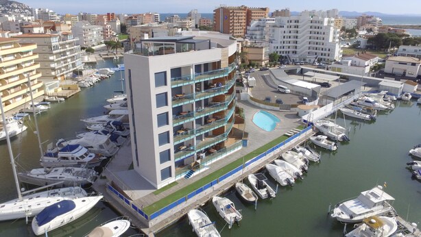 A modern hotel with multiple balconies overlooking a marina filled with boats.