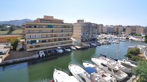 A marina with multiple boats docked, surrounded by multi-story buildings with balconies.