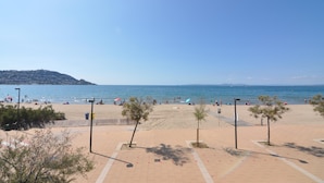 A beach with a paved walkway, trees, and a clear view of the sea. - Charming apartment for rent in Roses, Costa Brava! Ideal for 5 people, just 10 meters from the beach. Book now! (Rosas / Roses)