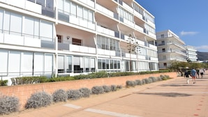 A multi-story hotel with balconies, a brick lower level, and a paved walkway. - Charming apartment for rent in Roses, Costa Brava! Ideal for 5 people, just 10 meters from the beach. Book now! (Rosas / Roses)