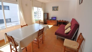 Una habitación con una mesa de comedor, sillas, un sofá, un televisor y una cama.