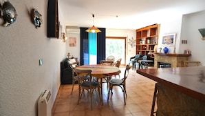 Un'area pranzo con un tavolo rotondo e sedie, una lampada a sospensione e una libreria.