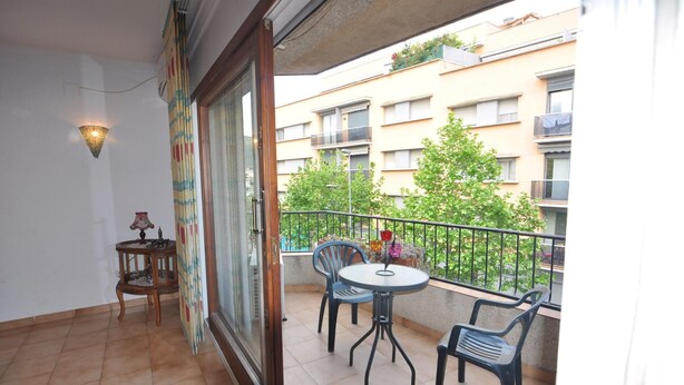 Un balcone con tavolo e sedie, un piccolo tavolino in legno e una pianta in vaso.