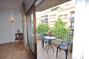 A balcony with a table and chairs, a small wooden side table, and a potted plant. - Vacation rental in Roses, Costa Brava: Spacious 2-bedroom apartment 300 meters from the beach. Equipped with terrace and barbecue. (Rosas / Roses)