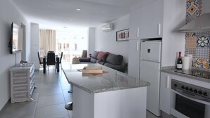 A modern kitchen with a central island, a dining area with a table and chairs, and a sofa in the background.