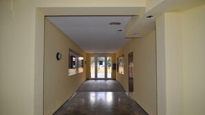 Um corredor com soalho em azulejos, portas e janelas nas paredes.