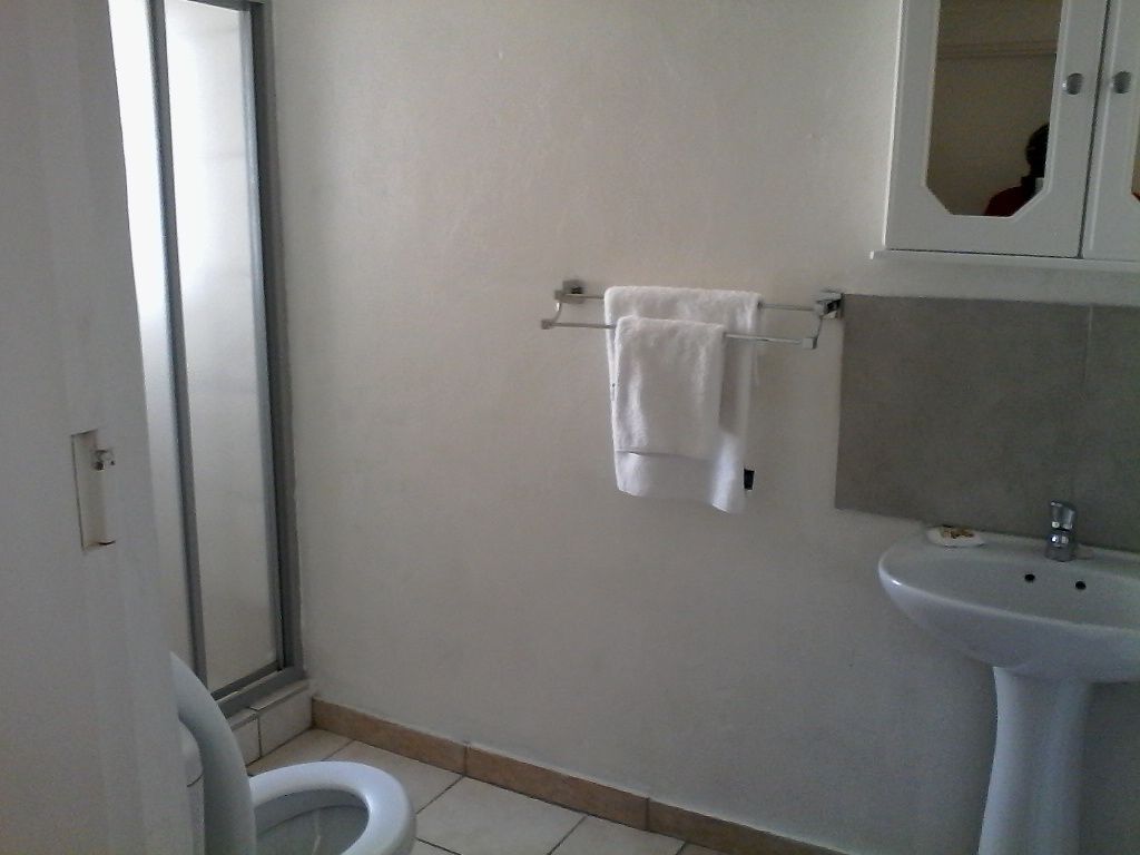 A bathroom with a toilet, a sink, and a towel rack with two towels.