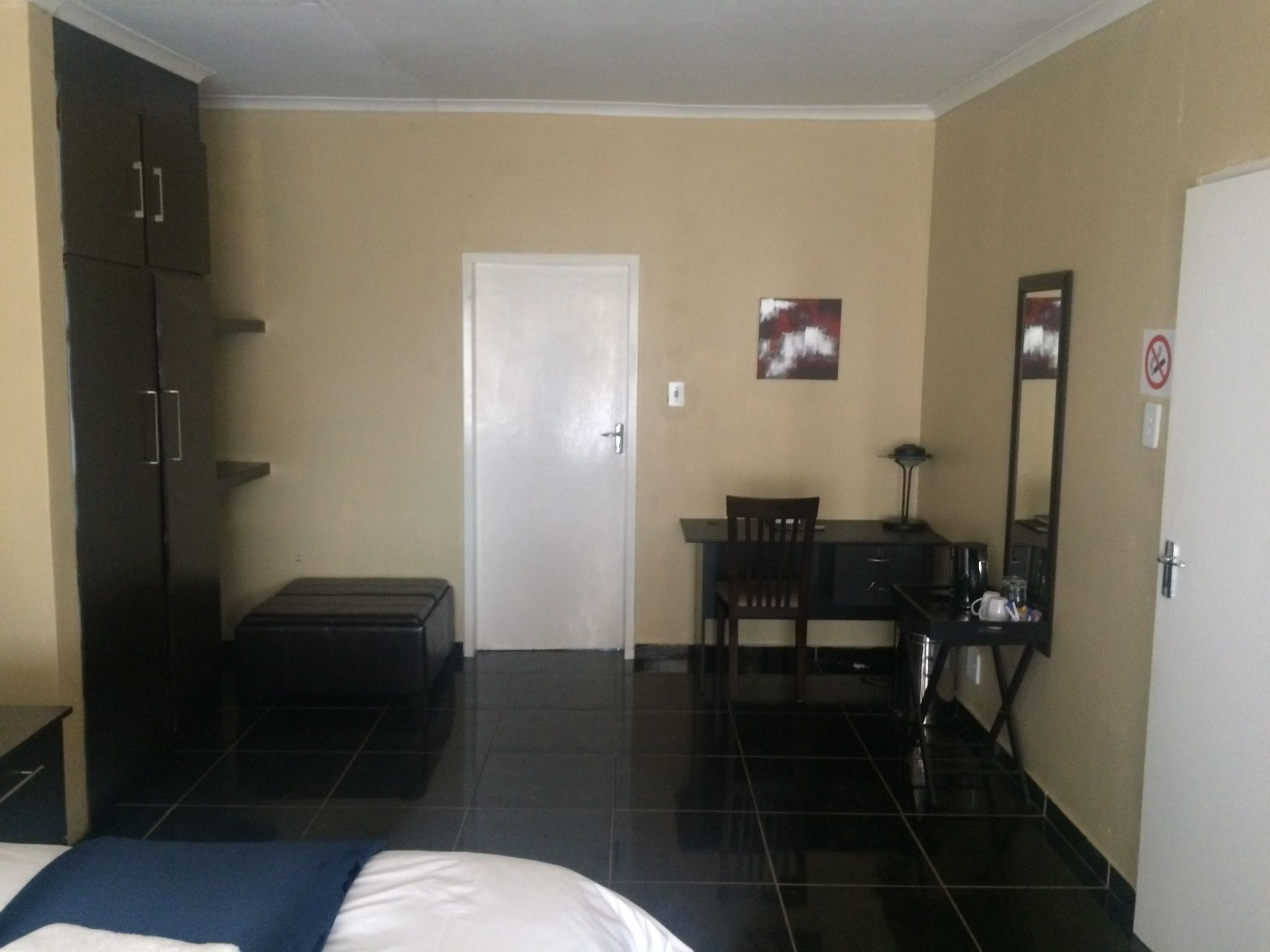 Une chambre d’hôtel avec un lit, un bureau, une chaise, une armoire et une porte.