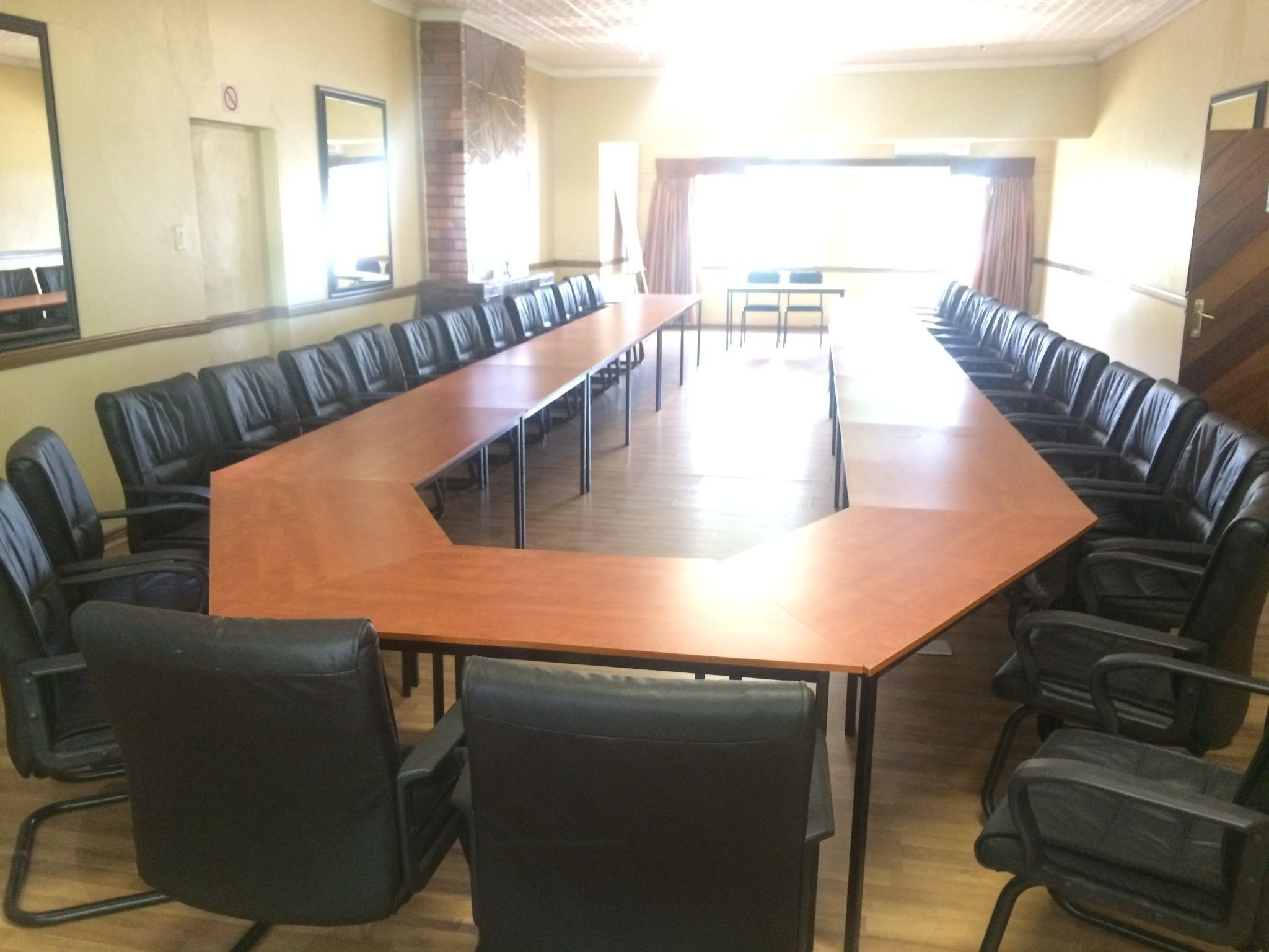 Un salón de conferencias con una larga mesa y sillas de cuero negro.
