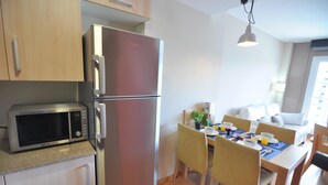 A compact kitchen with a refrigerator, microwave, and dining table with chairs.