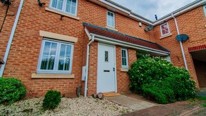 A two-story brick house with a white front door, a small porch, and a garden with green shrubs. - Harris House (Doncaster)