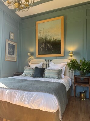 A bedroom with a large bed, two bedside tables, a chandelier, a painting, and a potted plant. - Château D'hodebert (Saint-Paterne-Racan)