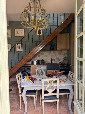 A dining area with a chandelier, a staircase, and kitchen cabinets. - Château D'hodebert (Saint-Paterne-Racan)