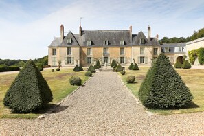 A large, historic building with a symmetrical facade, a gravel pathway leading to the entrance, and neatly trimmed topiary trees. - Château D'hodebert (Saint-Paterne-Racan)