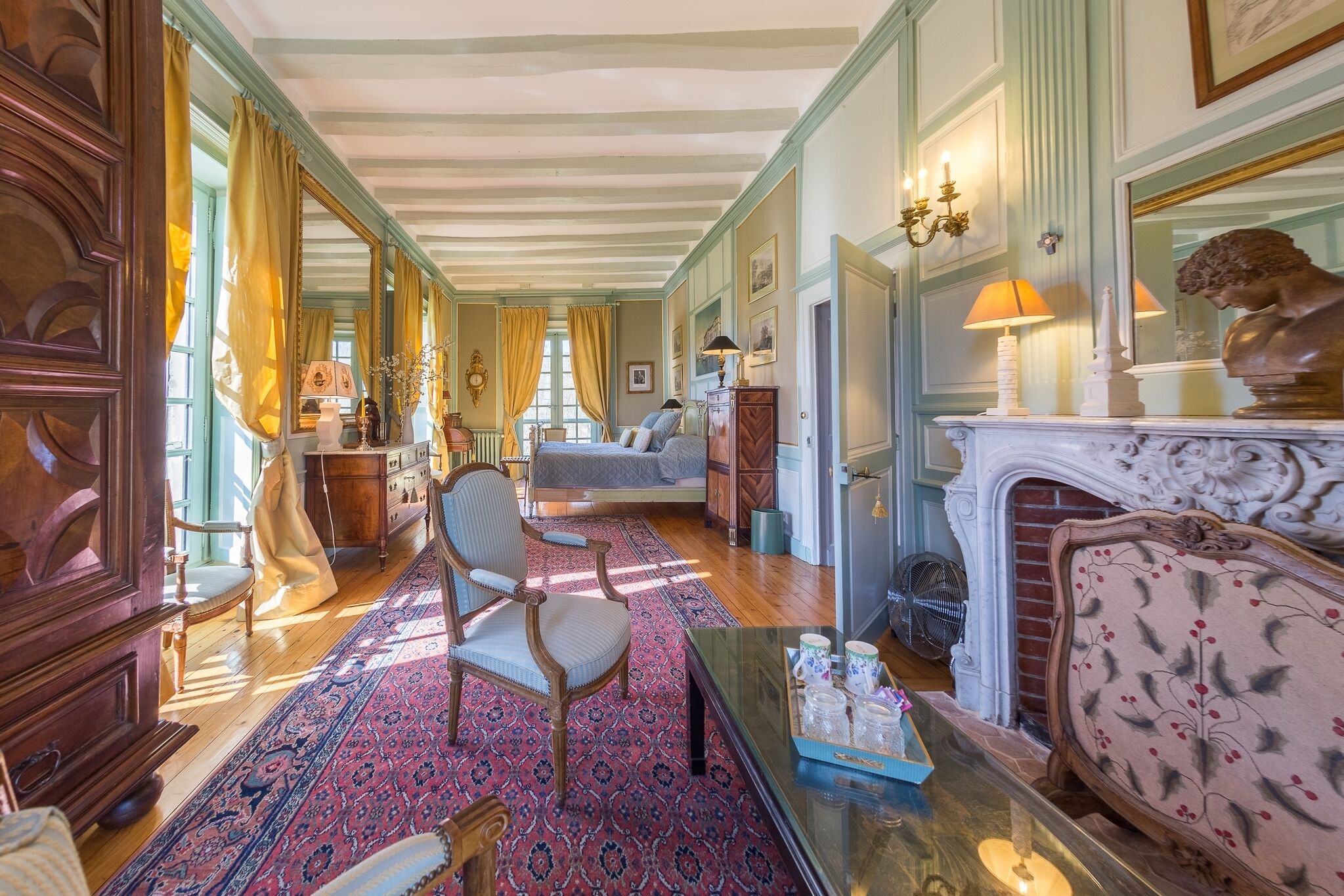 A spacious room with a large window, a fireplace, and a classic wooden chair.