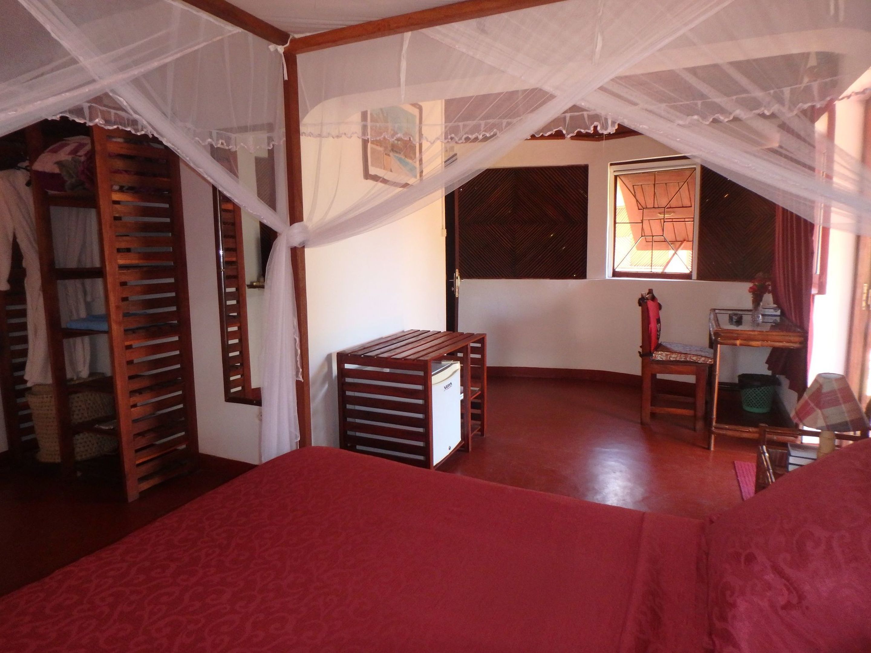 Une chambre à coucher avec un lit à baldaquin, des meubles en bois et une armoire avec un miroir.