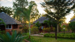 A resort with thatched-roof huts, a well-maintained garden, and a pathway leading to the buildings. - Edena Kely (Mahajanga)